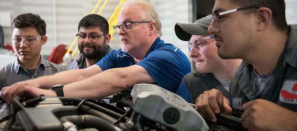 professor and students looking at engine