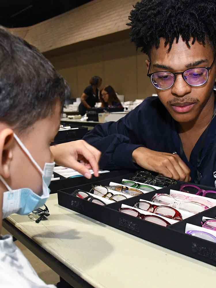eye care tech helping young boy choose glasses
